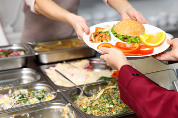 Symbolbild: Mittagsgericht wird über den Kantinentresen gereicht.